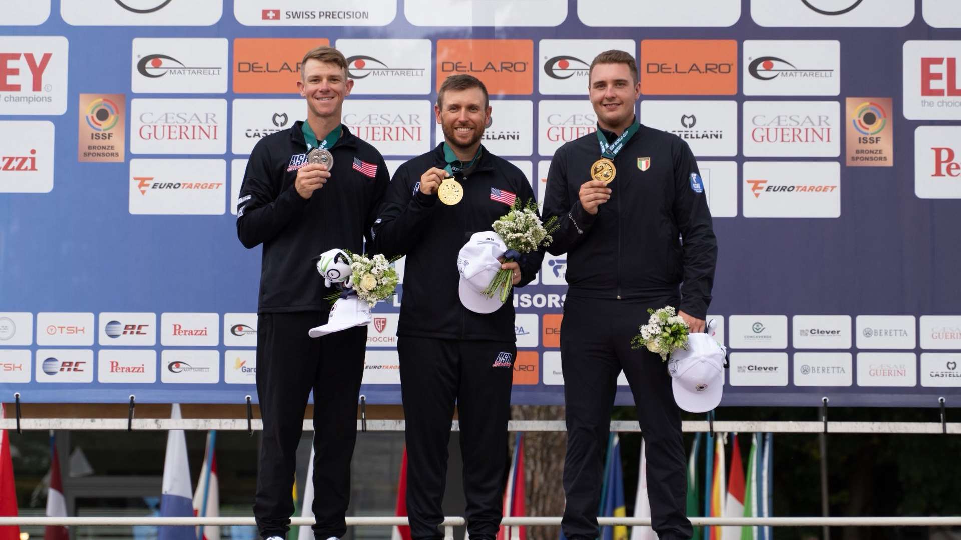 Vincent Hancock, Christian Elliott and Erik Pittini holding their medals on the Men's Skeet podium at the 2026 ISSF World Cup Shotgun in Lonato, Italy