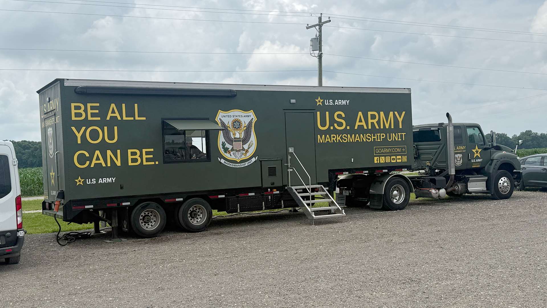 A U.S. Army Marksmanship Unit semi-truck and trailer with "Be All You Can Be" lettering parked on gravel at the Cardinal Shooting Center