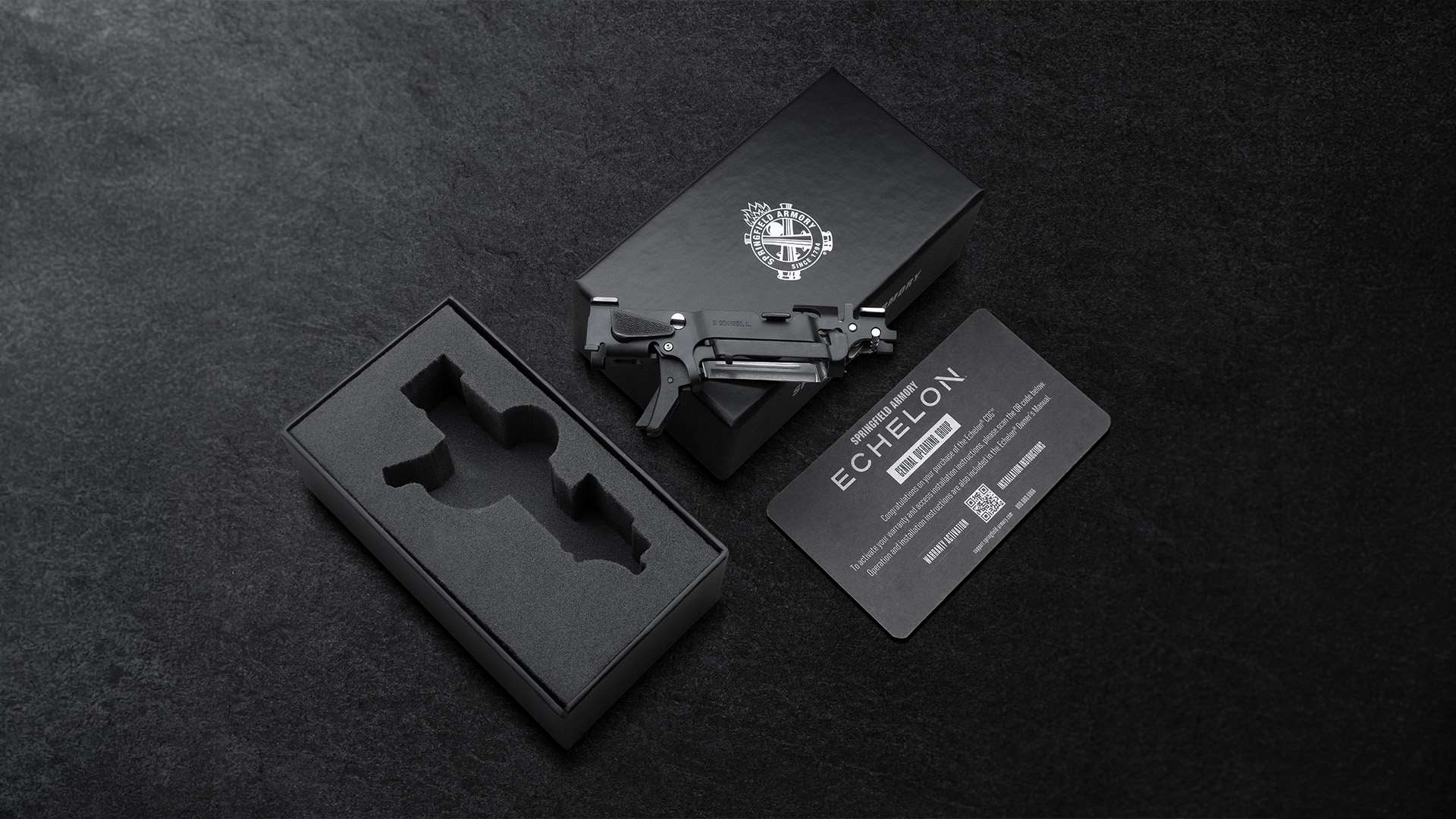 Springfield Armory Echelon Central Operating Group resting on its black retail box beside a foam-lined tray and a printed Echelon instruction card with a QR code