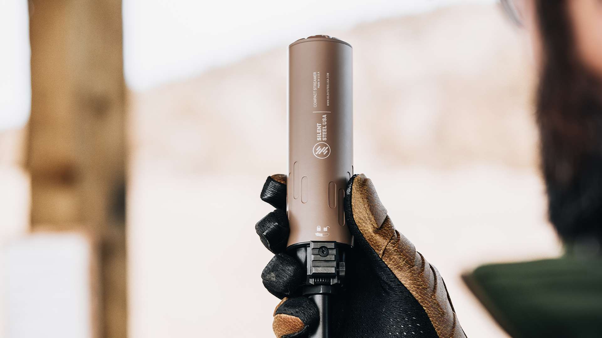 A man unscrews a Silent Steel USA Compact Streamer suppressor from his rifle