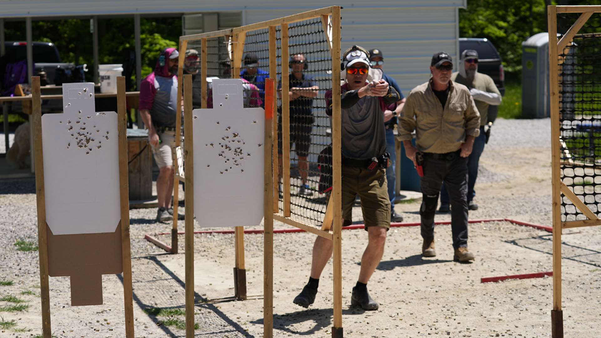 A USPSA shooter performs a stage walkthrough alongside steel targets and no-shoot targets before firing