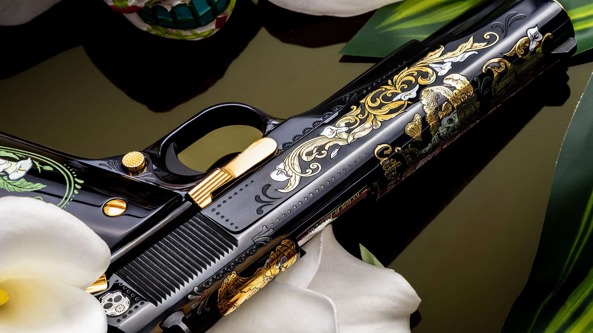 Close-up of the left side of the SK Guns La Catrina 1911 slide, showing gold and silver calla lily scrollwork, a gold skeletal figure in a feathered hat, a gold figure in a ruffled gown, a small silver sugar skull near the rear serrations and gold controls