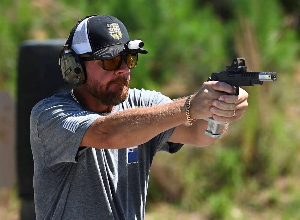 Billy Herrington fires a pistol during a USPSA competition stage