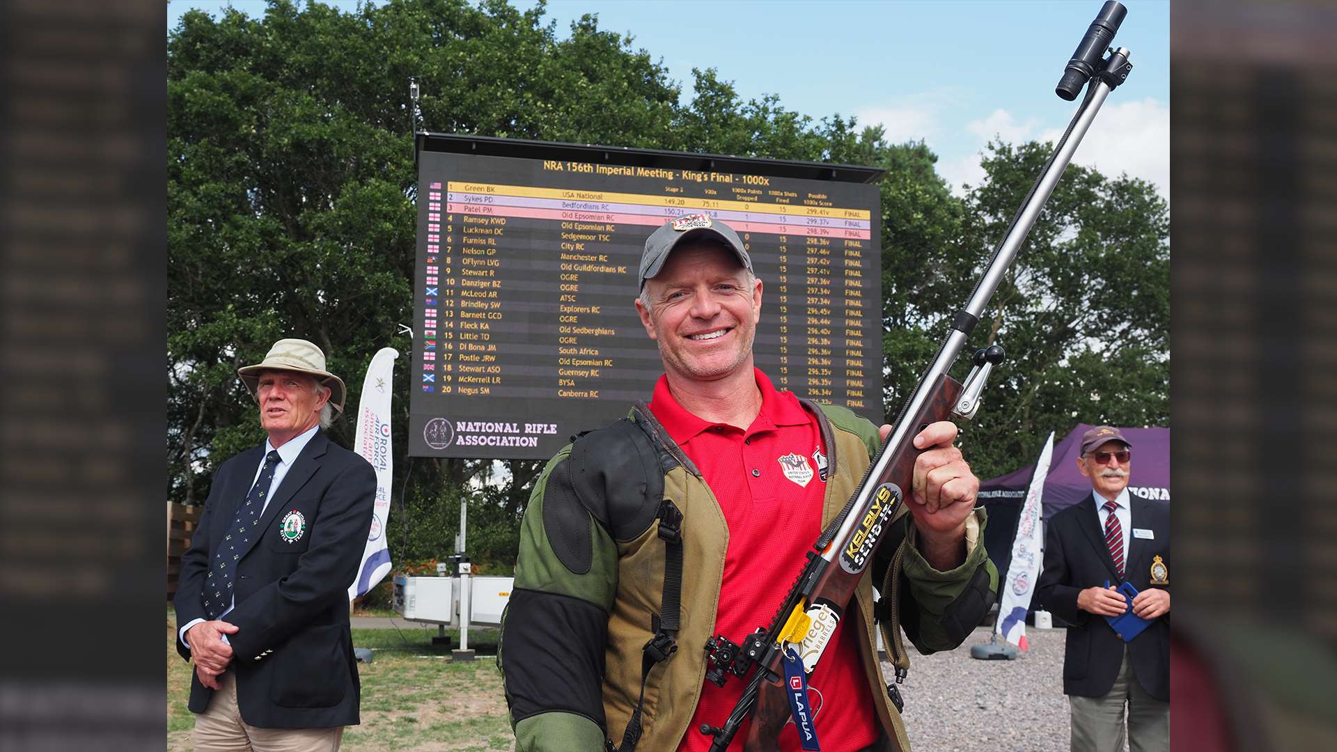 Brandon Green holds his target rifle while standing in front of a leaderboard listing the top 20 finishers of the 156th Imperial Meeting King's Final, with his name in first place