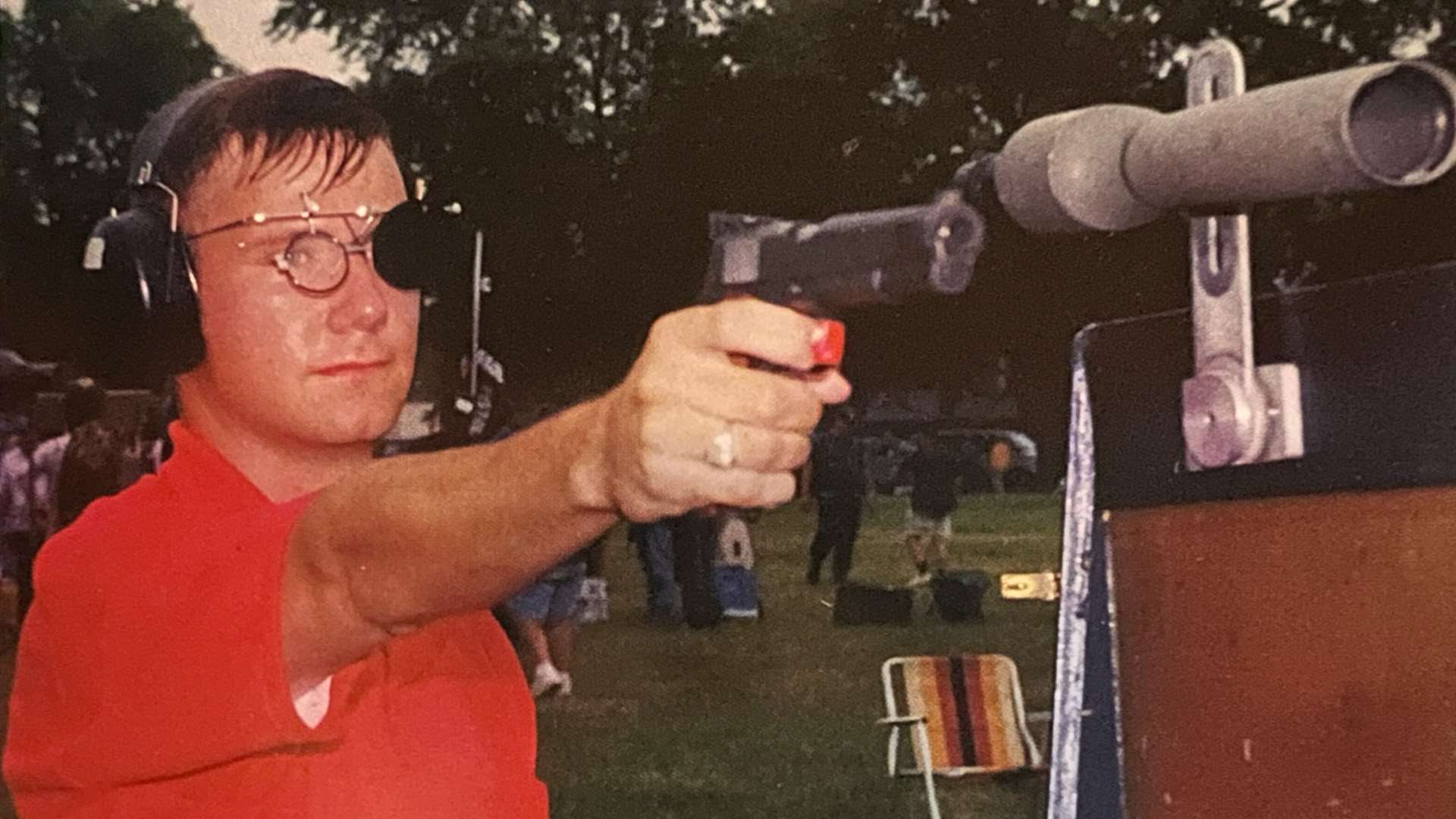 John Bickar holding his pistol and next to it is a spotting scope at Camp Perry, Ohio