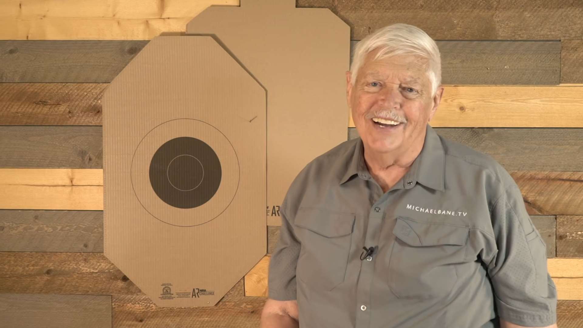 Michael Bane on the set of Triggered with an NRA America’s Rifle Challenge cardboard target behind him during episode covering ARC at A Girl and A Gun conference and Match Director Summit