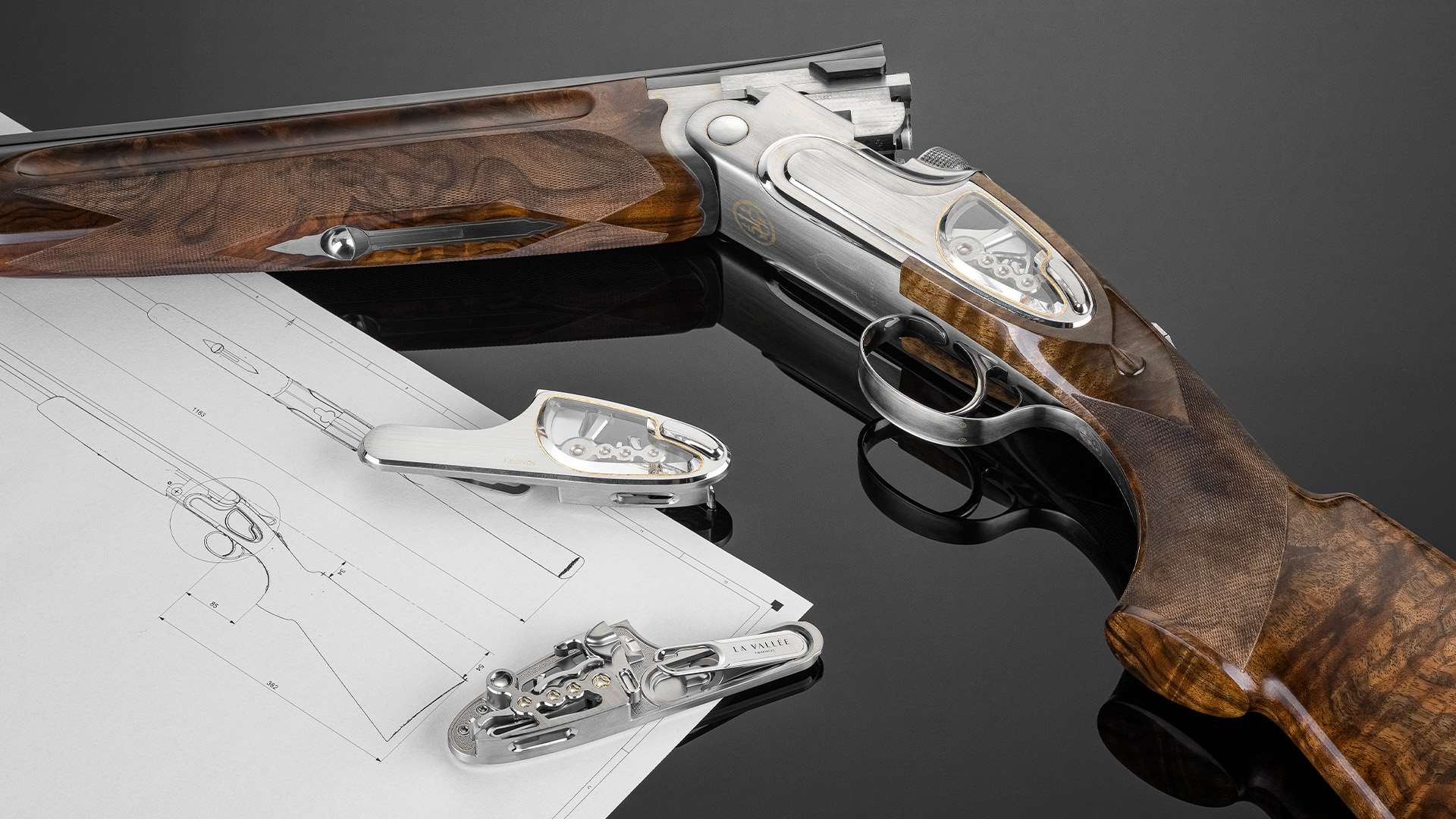 A detached sideplate with a sapphire window and a La Vallée-marked lock mechanism lying on a technical drawing next to the Beretta SO10 Kronos shotgun