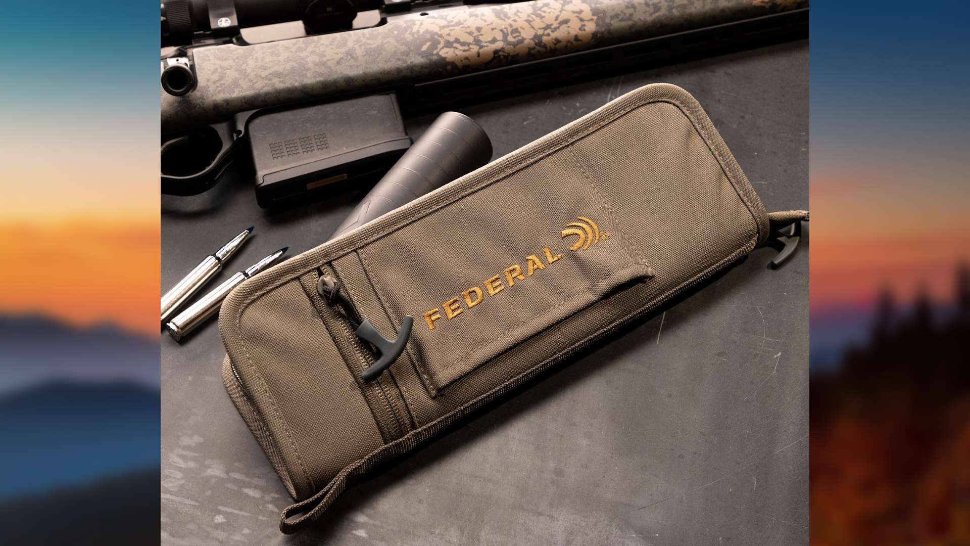 Federal Suppressor Case in Coyote Tan photographed on a dark surface beside a camouflage bolt-action rifle, a detached black suppressor, a rifle magazine and two cartridges.