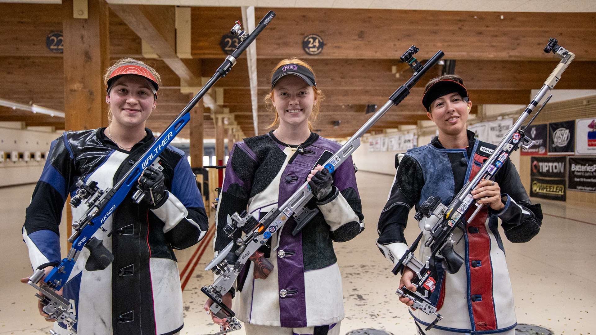 Three female smallbore competitors in shooting jackets hold their rifles upright on the range at the 2026 Rifle Fall Selection Match