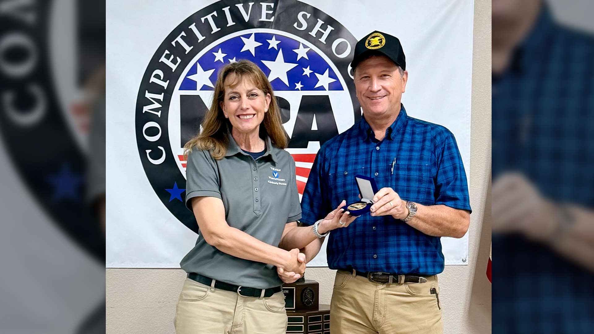 Kim Rowe shakes hands with NRA First Vice President Mark Vaughan while receiving the Patriot Minuteman Trophy medal at the 2026 NRA Mid-Range Nationals