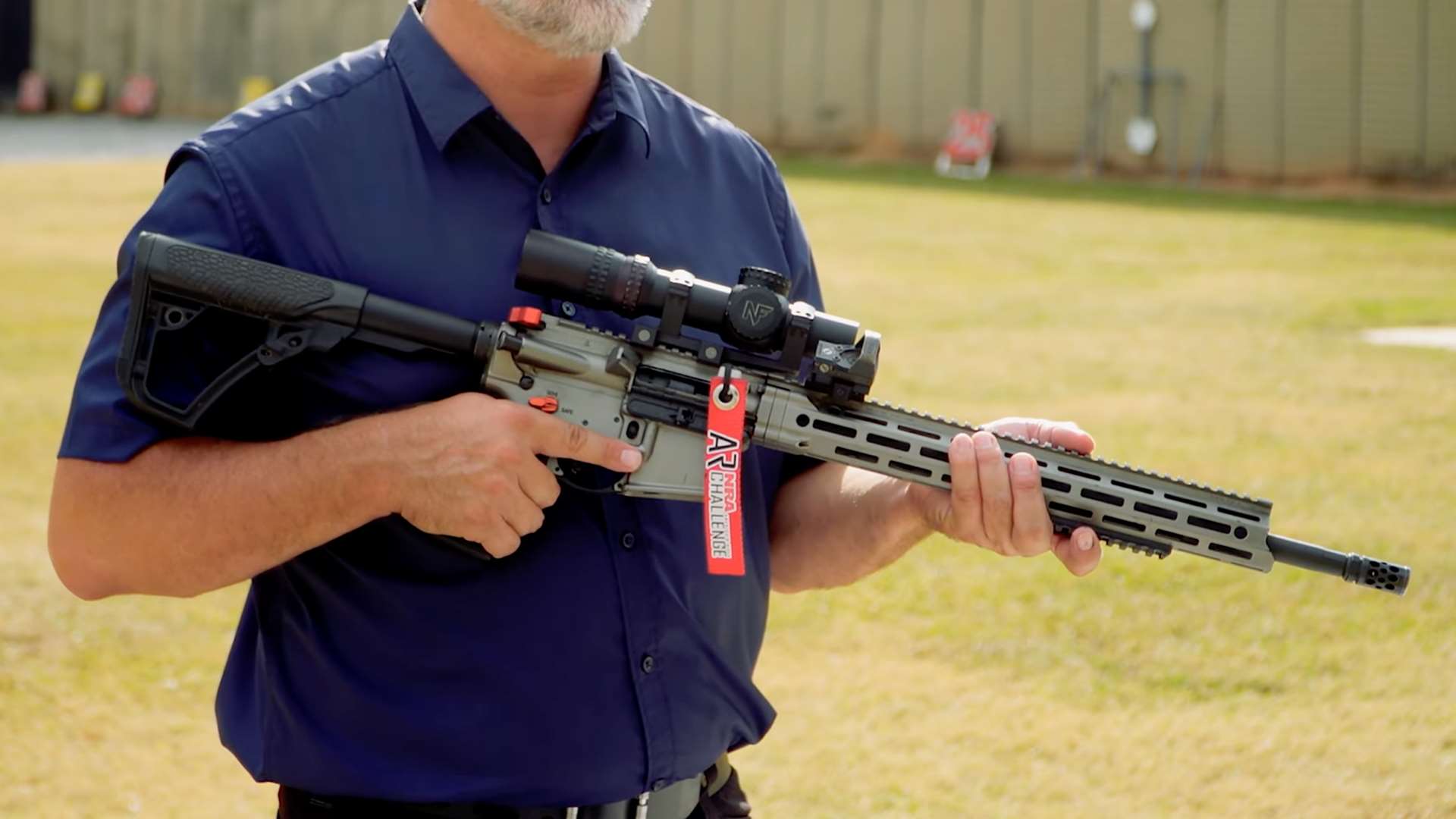 Ryan Muller holding an AR-15 configured for NRA America’s Rifle Challenge Open division with magnified scope and offset sight