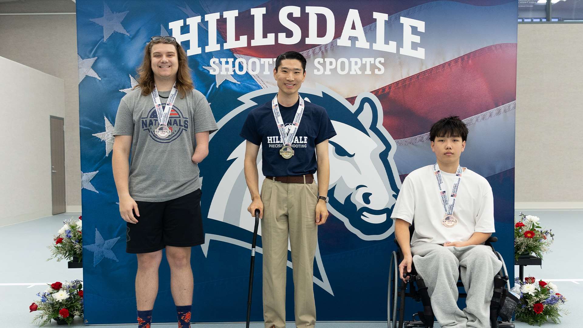 YanXiao Gong stands atop the center podium with gold medals between the silver and bronze para pistol finishers