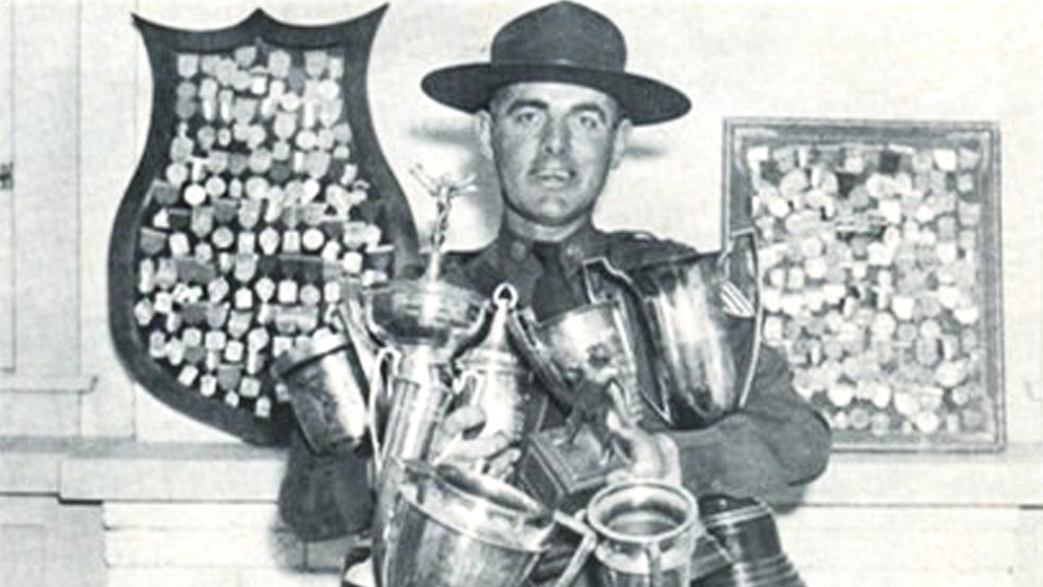 Legendary competitor Col. Charles Askins holding an armful of trophies at Camp Perry in 1937.