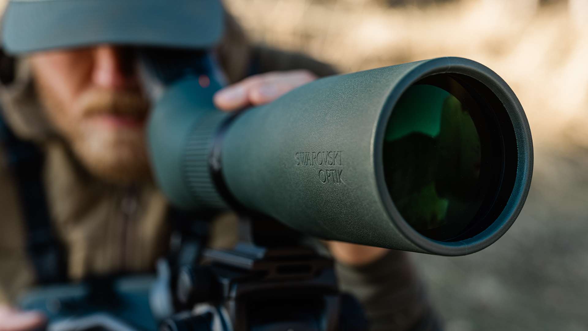 Close-up of a hunter glassing through the Swarovski AT Endura spotting scope with the 75 mm objective lens facing the camera