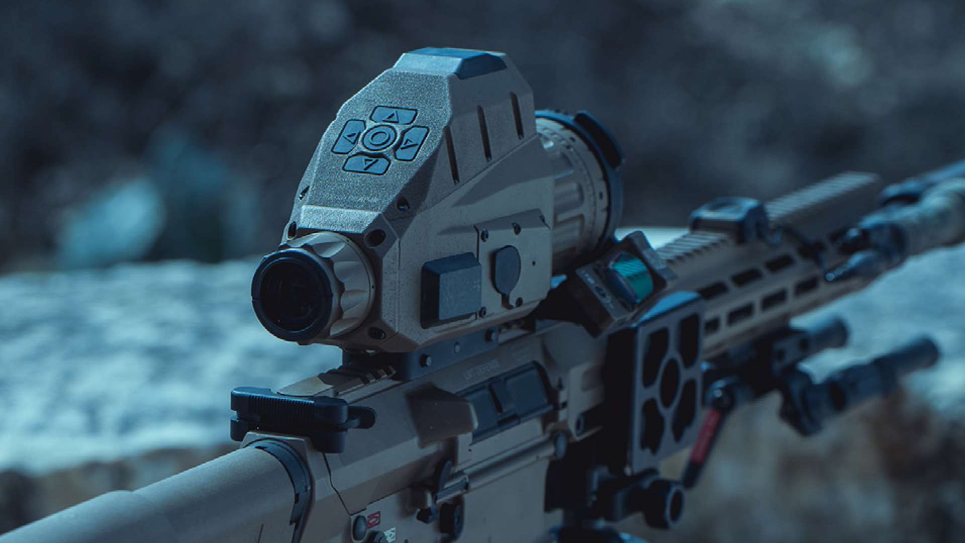 Close-up rear view of a tan Trijicon REAP-IR-50LRF thermal riflescope with a five-button keypad, mounted on a rifle at dusk