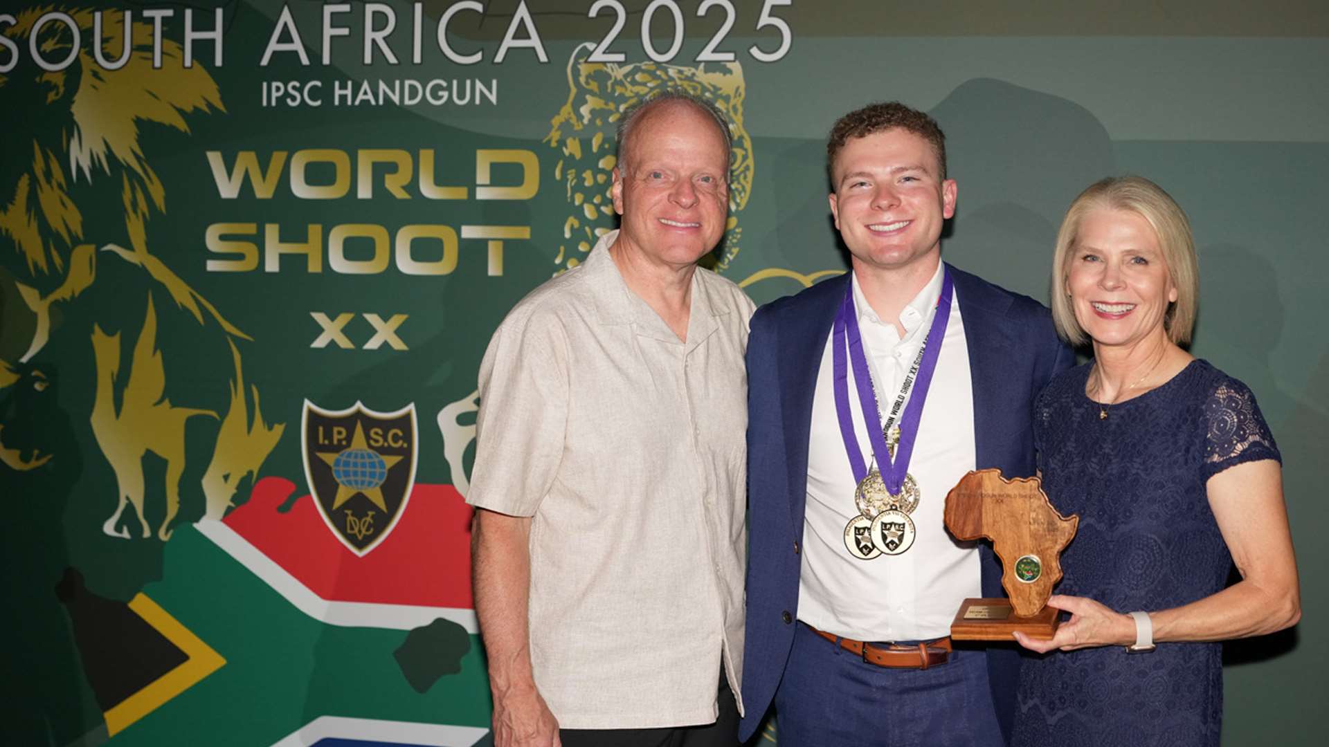 Christian Sailer poses with his parents at the 2025 IPSC Handgun World Shoot awards ceremony in South Africa