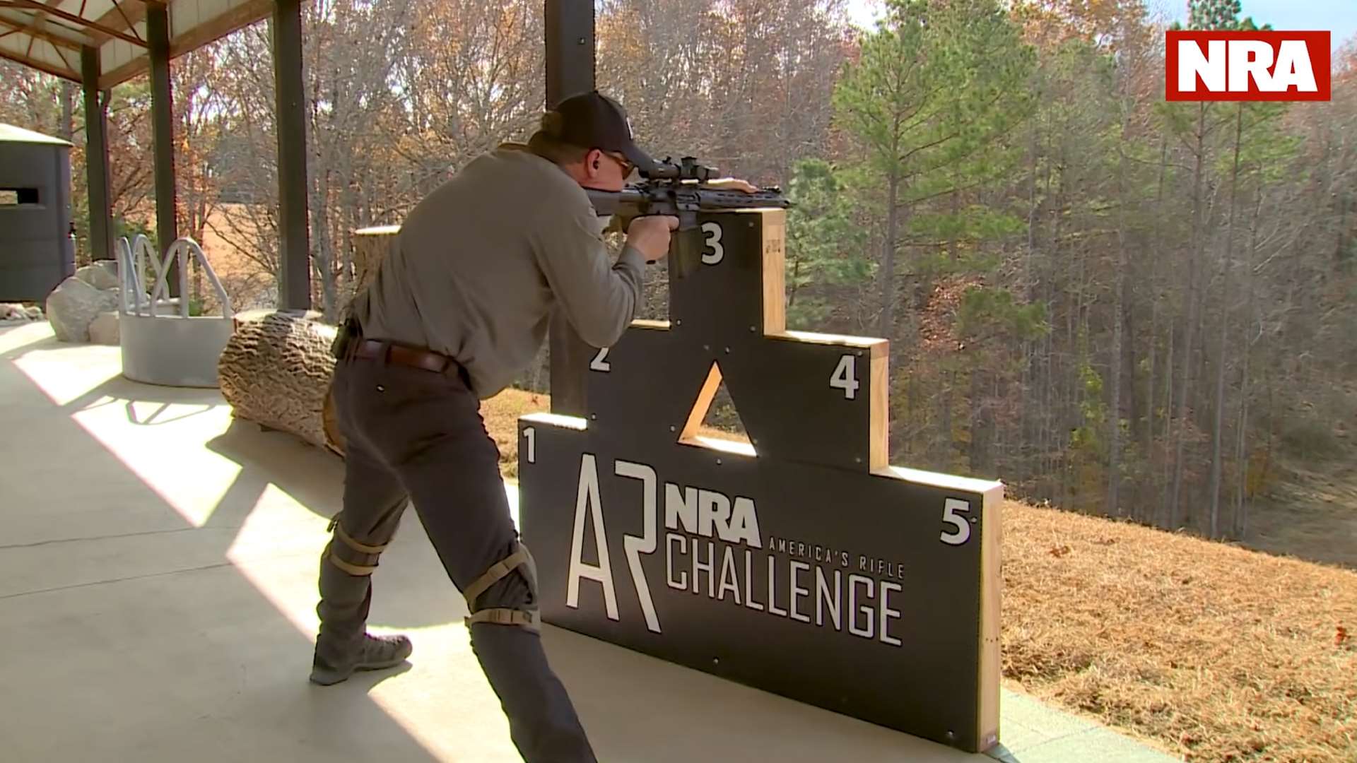 Kyle Lamb shooting from standing position on NRA America's Rifle Challenge barricade showing locked-knee stance and rifle placement technique