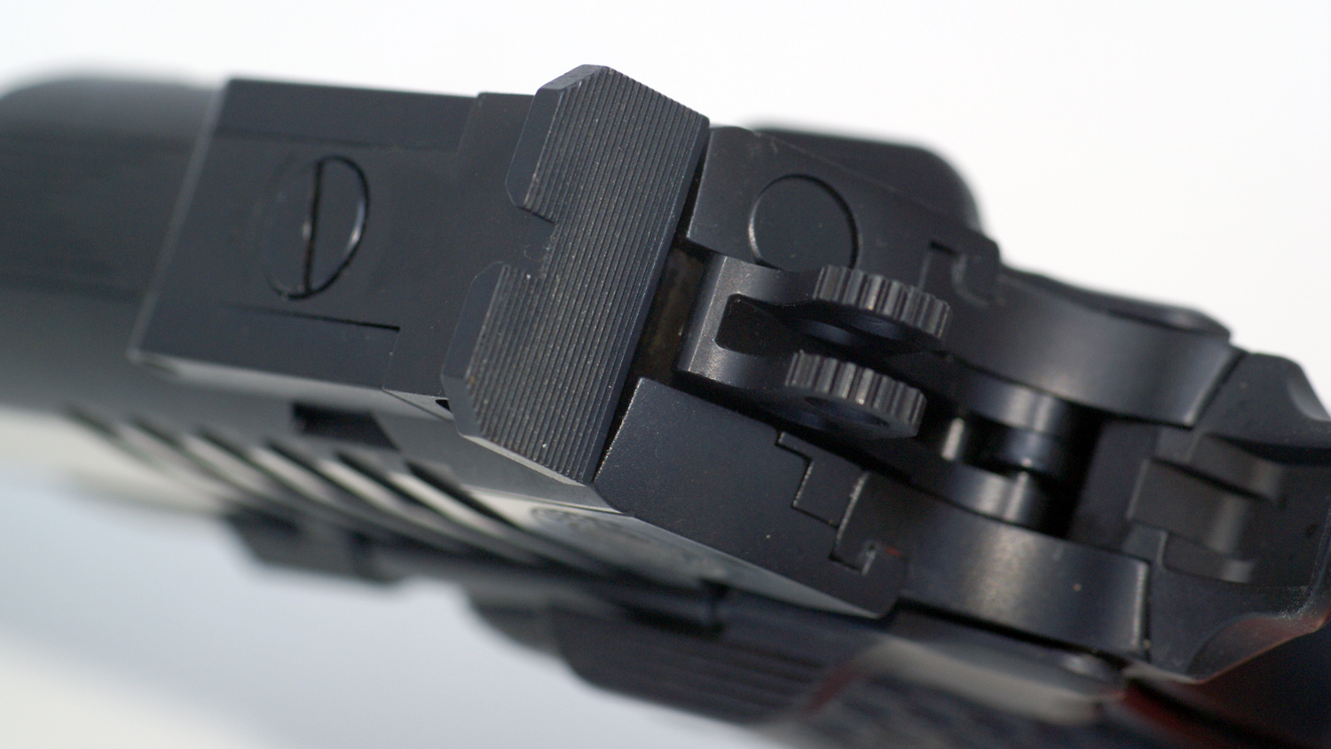 The fully-adjustable Bomar-style rear sight features a serrated plain black blade.