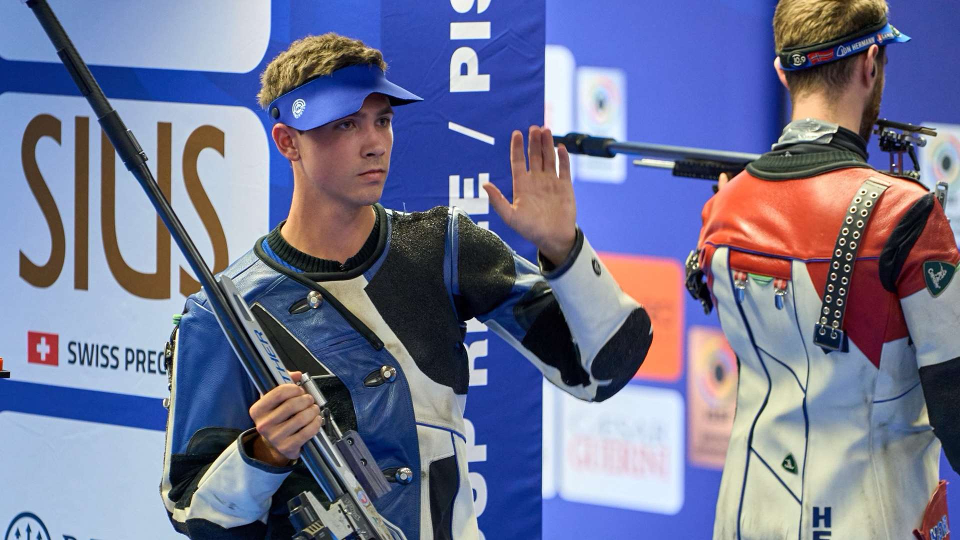 Braden Peiser raises his hand to the crowd while holding his Walther rifle at the 2026 ISSF World Cup in Munich