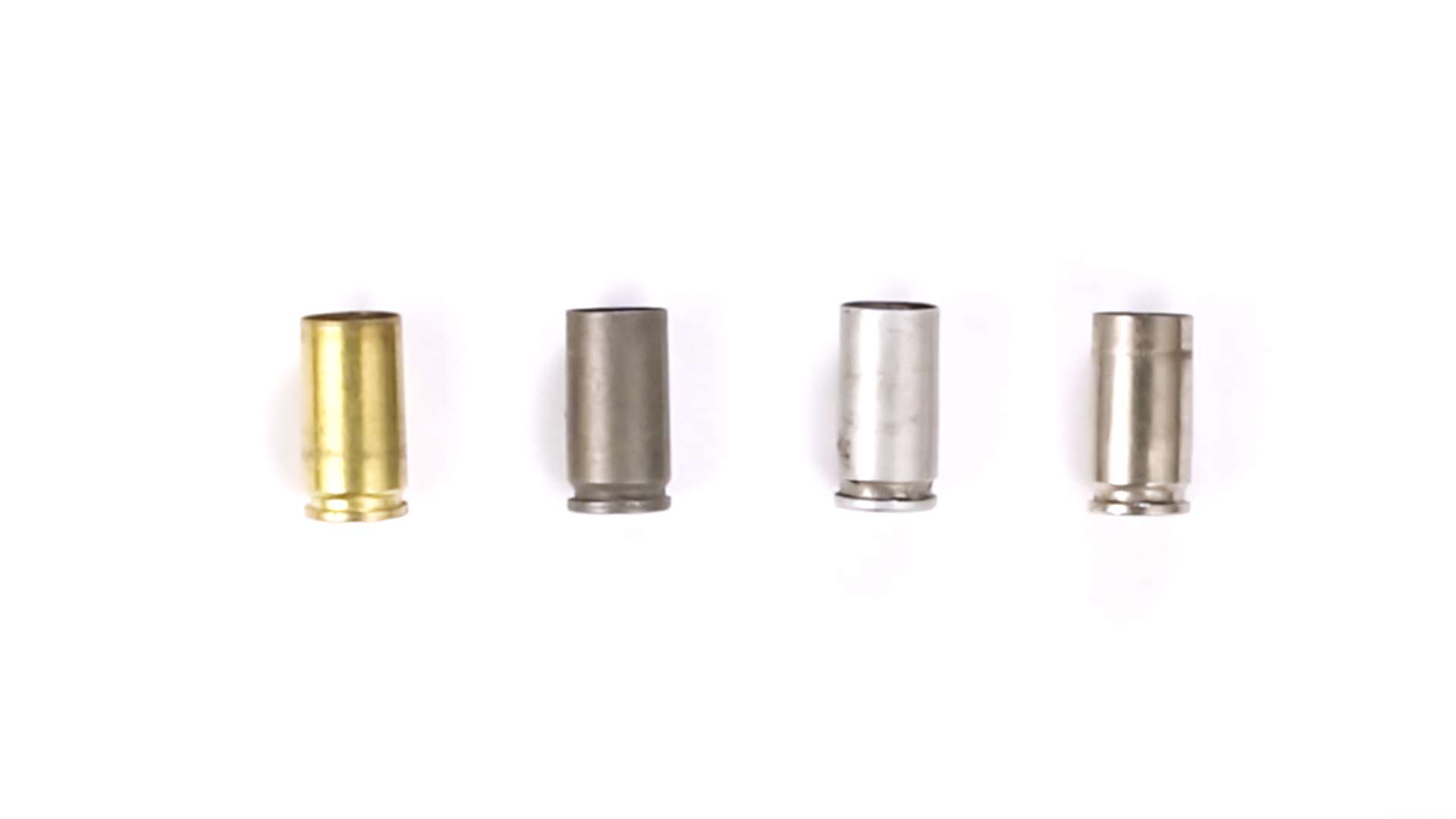 Four cartridge cases showing the different case materials used in ammunition: brass, steel, aluminum and nickel-plated brass, each with a distinct color and finish.