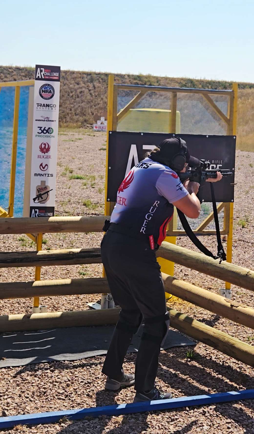 Randi Rogers shooting a Ruger Harrier AR-pattern 5.56 mm NATO rifle over a wooden barricade at the 2026 NRA Faces of Freedom ARC Regional Championship in South Dakota