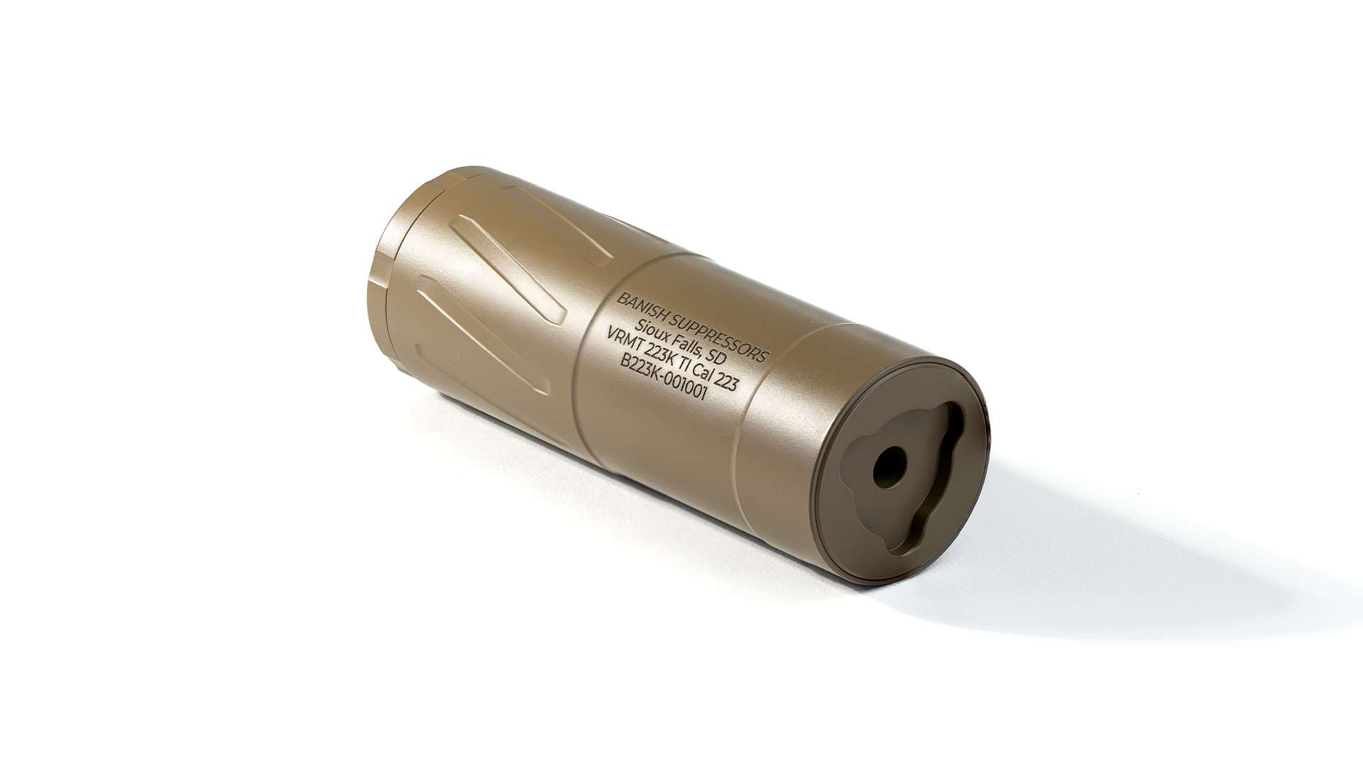 A flat dark earth titanium BANISH VRMT 223K Ti rifle suppressor lying on a white background, engraved with the Banish Suppressors name and Sioux Falls, SD address, muzzle end facing forward