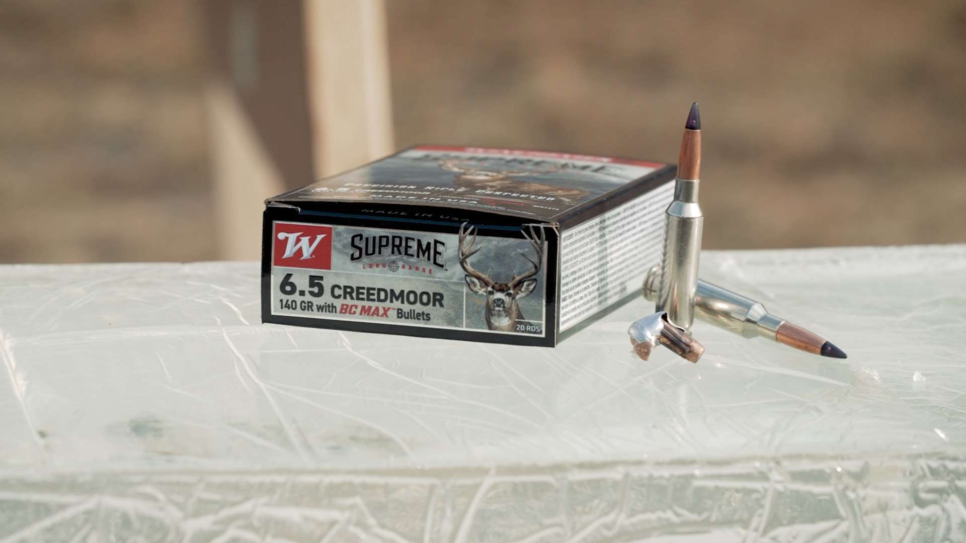 Winchester Supreme Long Range 6.5 Creedmoor 140-grain ammunition box on top of a ballistic gelatin block with two loaded cartridges and one recovered expanded bullet