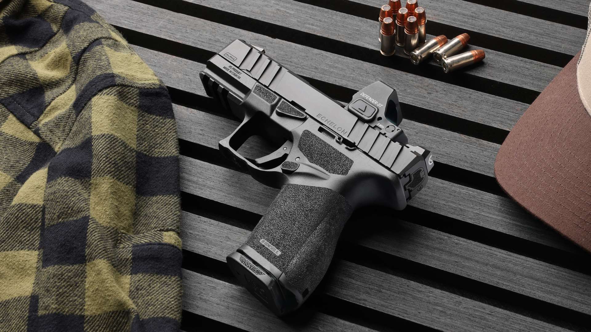 Springfield Armory Echelon Alpha 4.0C handgun shown with a mounted Defender-ST red-dot sight on a wooden slat surface, photographed beside flannel fabric, hollow-point ammunition and a hat